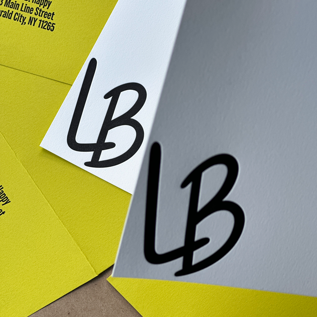 Notecards printed in Black Ink showing two initials L and B being held over envelopes.