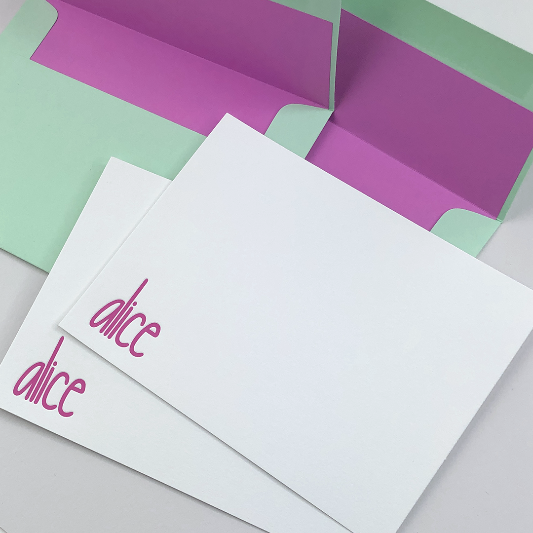 A flat lay image of two cards and two envelopes. The cards have the name alice printed in purple ink in the bottom left corner.
