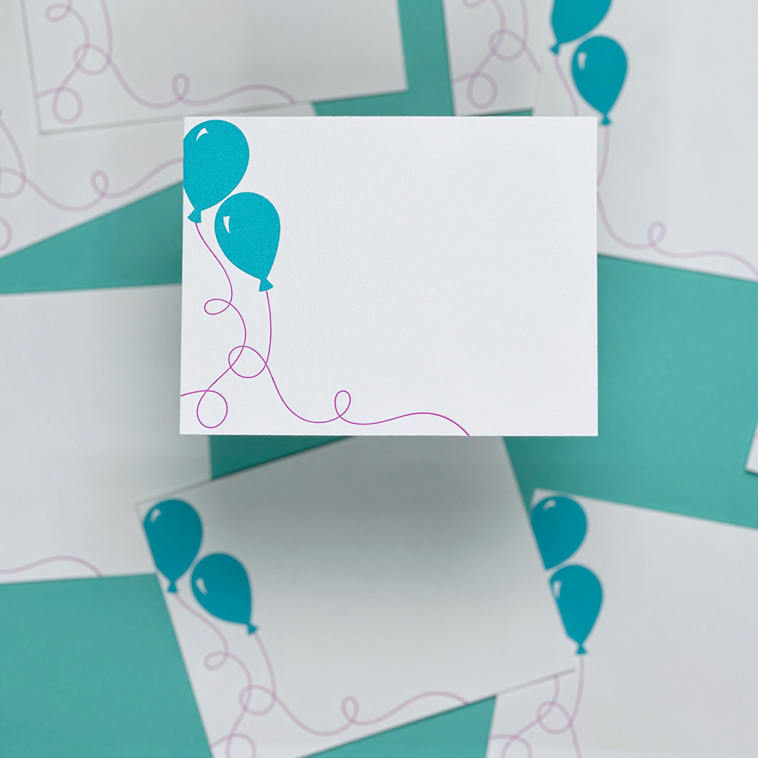 An image of stationery featuring blue balloons  with purple string